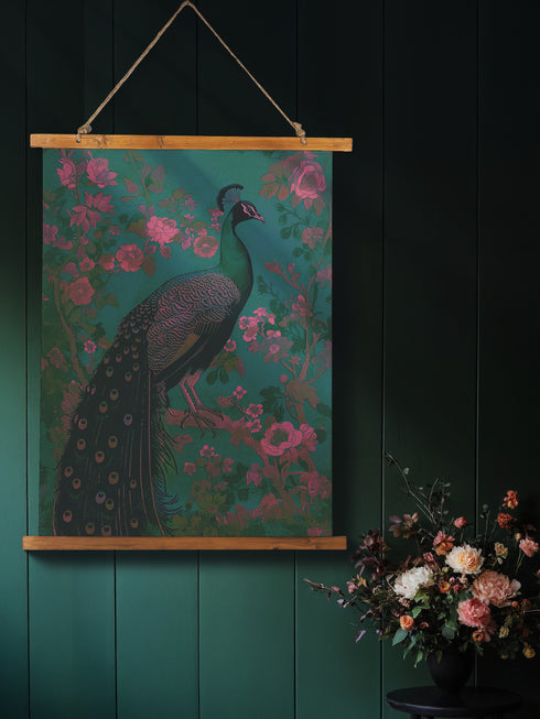 A wall tapestry featuring a detailed teal peacock with golden accents and intricate plumage, surrounded by ornate golden flowers and foliage on an emerald green background, mounted between wooden dowels with twine.